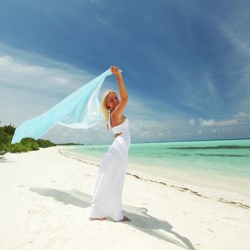 woman with a white fabric in his hands on the beach
