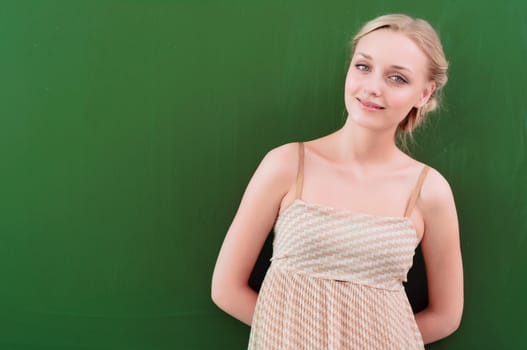 portrait of a young teacher near blackboard, looking at the camera and smiling