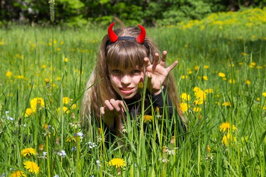 little devil girl in a green dandelion field