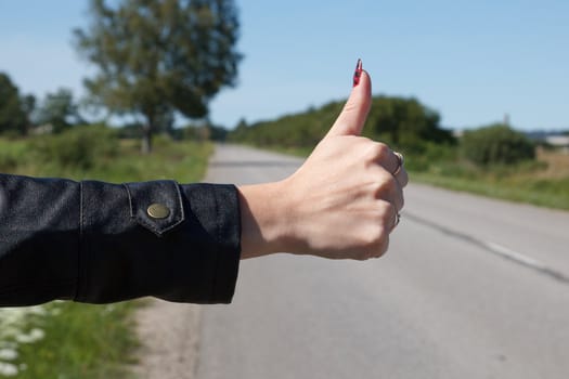 woman  holding out his thumb hoping to catch a rid
