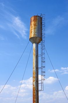 Large old metal water tower on the background of blue sky