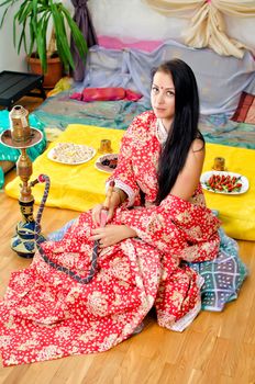 Young Indian girl in traditional red clothing with Hookah