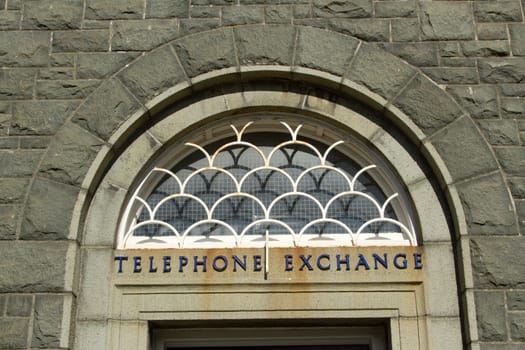 A doorway arch and stone wall with a sign with the words 'TELEPHONE EXCHANGE'.