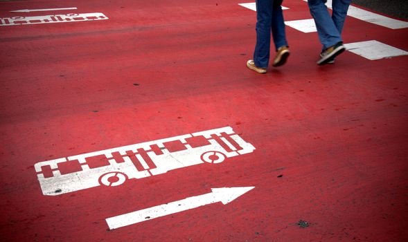 Red crosswalk with bus and traffic direction signs