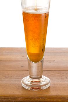 Cool glass of beer or lager being poured on a wooden bar top