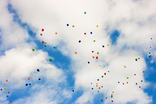 multi-colored balloons in the blue sky with white clouds