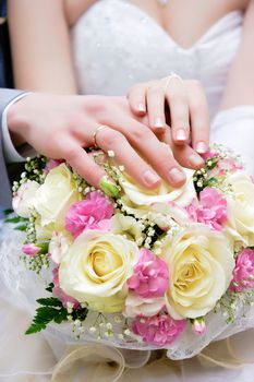 hands of newlyweds at the wedding bouquet