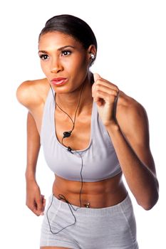Beautiful running African female athlete with toned muscular fitness body in grey with headset listening to music while exercising, isolated.