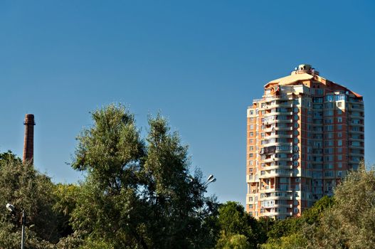 Building and chimney, among the Green, against the blue sky.