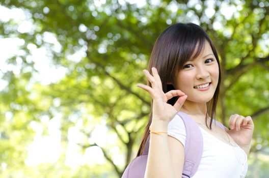 Cheerful Asian college student giving a okay hand sign