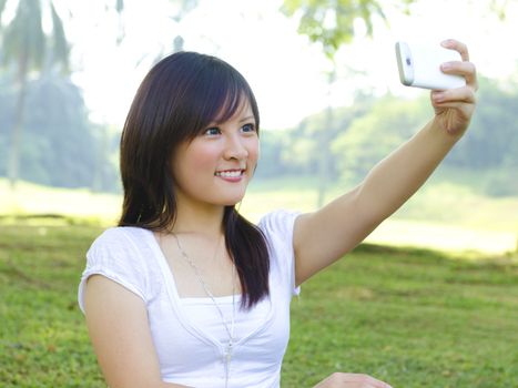 Asian girl self photographing, outdoor green park