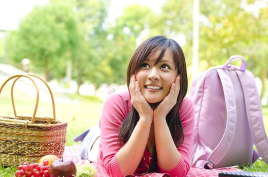 Young Asian student studying on campus lawn