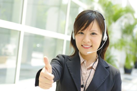 Friendly Customer Representative with headset thumb up during a telephone conversation.