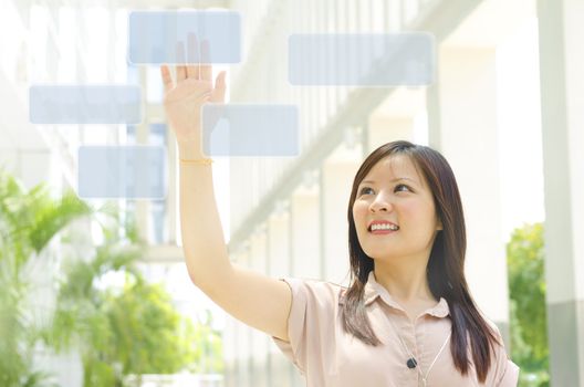Young Asian woman finger pressing on touchscreen monitor