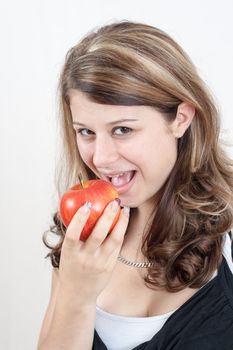 young brunette girl eating a apple on white background