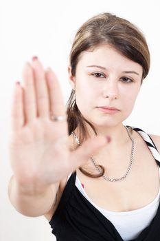 young brunette girl with brown eyes is showing the stop gesture on white background