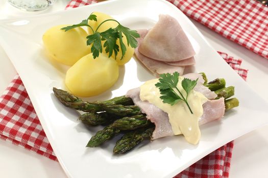 Asparagus with hollandaise sauce, cooked ham, potatoes and parsley
