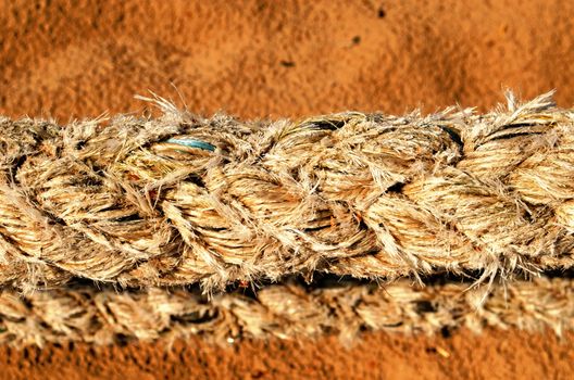 Closeup of thick synthetic rope and sea sand on background.