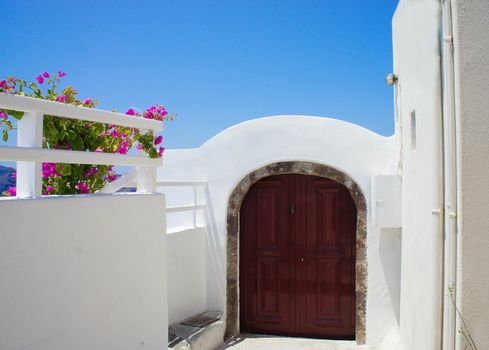 Santorini terrace with pink beautiful flowers and small doors