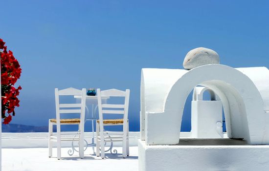 Santorini cosy terrace with two chairs and flowers
