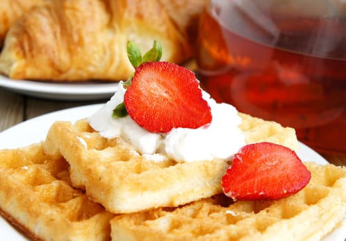 Tasty breakfast - tea, croissants, wafers with cream and strawberries             