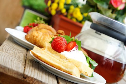 Sweet desset - tea, croissants, wafers with cream and strawberries
           