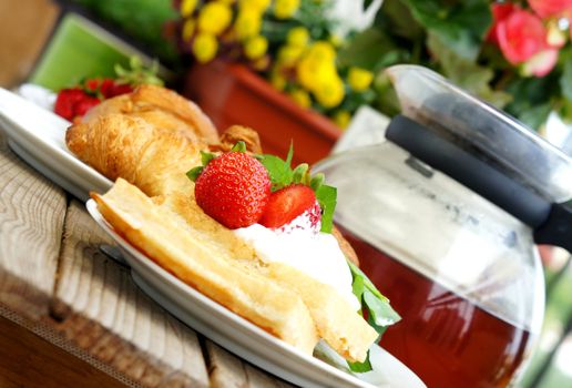 Tasty breakfast - tea, croissants, wafers with cream and strawberries                   
