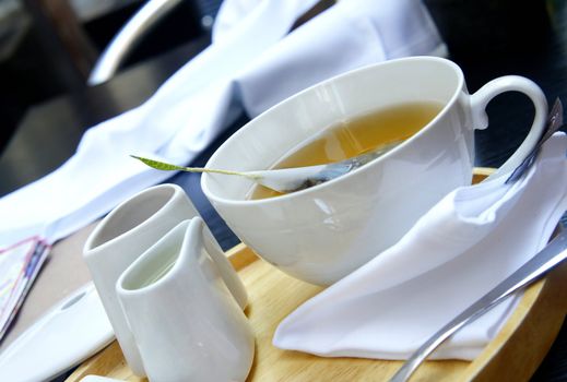 Tea time - green organic tea, white tea service, wooden try, white tablecloth        