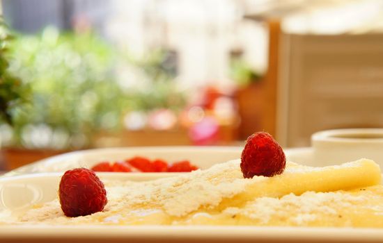 Tasty breakfast with pancake, raspberry, strawberry and powdered sugar             