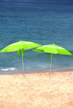 Sea time - two green sun umbrellas on the beach 