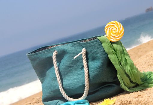 Summer holidays - blue beach bag on the seacoast with lollipop