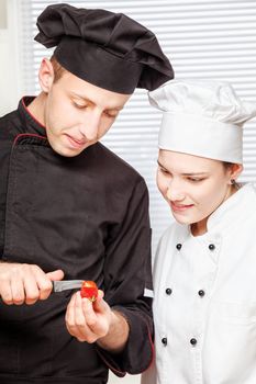 Senior chef teaches young chef to decorate strawberry