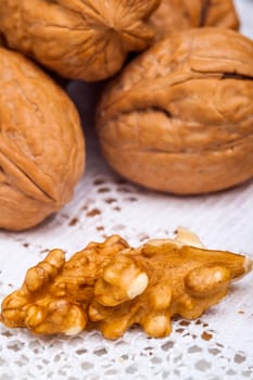 A composition of walnuts, cracked walnuts over a background of white cloth