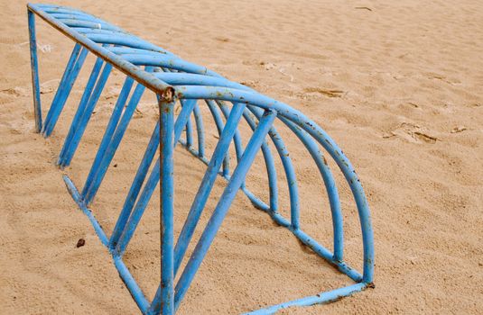 Blue steel empty bicycle parking place on sea sand in beach.