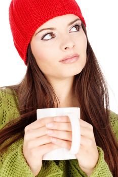 young brunette woman in wool sweater and cap holding a teapot, isolated on white