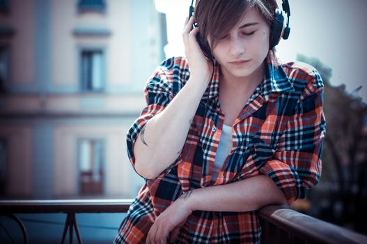young hipster woman listening to music on balcony
