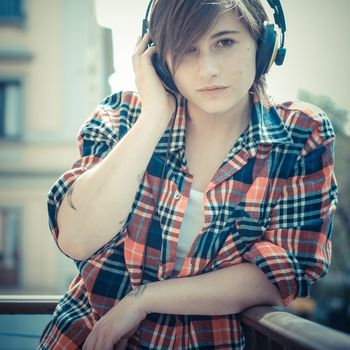 young hipster woman listening to music on balcony