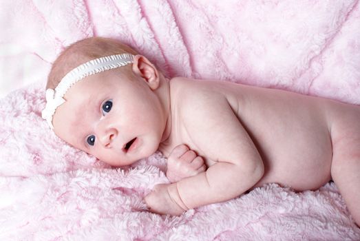 A one month old new born rests happily in her blanket.