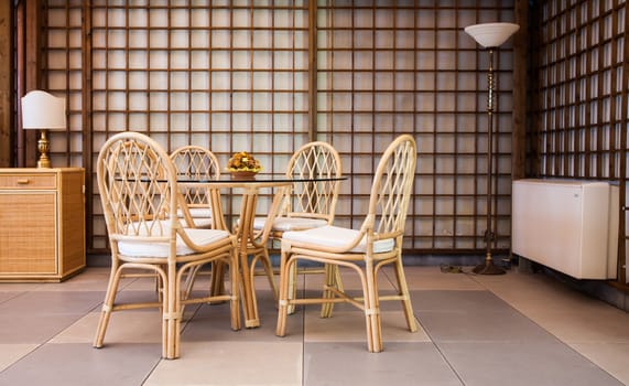 Glass table with wickler chairs in an elegant interior