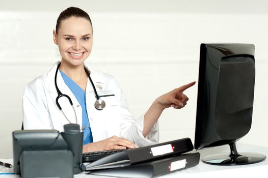 Female professional pointing at lcd screen with stethoscope around her neck
