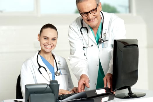 Team of doctors working on computer. Woman typing on keyboard and man arranging files