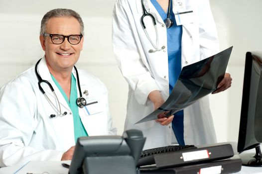 Woman assistant presenting x-ray report to male doctor. Indoor shot