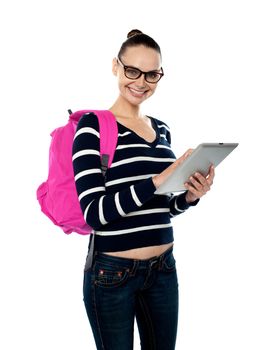 Smiling female student playing on touch screen device against white background