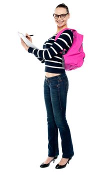 Teenage college student writing notes, full length portrait