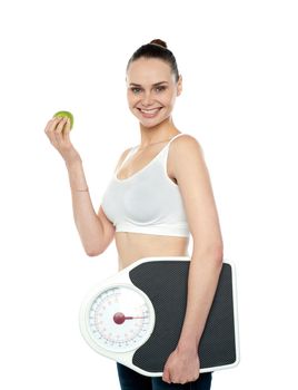 Attractive woman with apple and weight scale smiling at camera