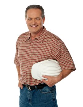 Smiling senior architect holding white safety hat posing casually