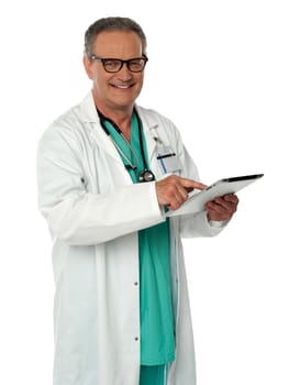 Cheerful doctor using wireless tablet device looking at you