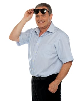 Casual man holding sunglasses over his head smiling at you