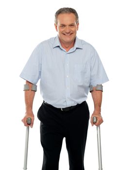 Senior man standing with support of crutches isolated against white background