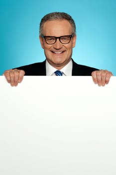 Corporate man standing behind big blank billboard wearing eyeglasses